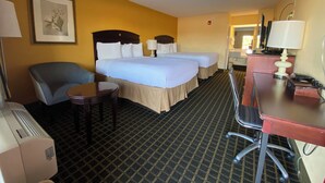 A hotel room with two beds, a desk, a chair, and a small table. - Travel Inn (Unadilla)