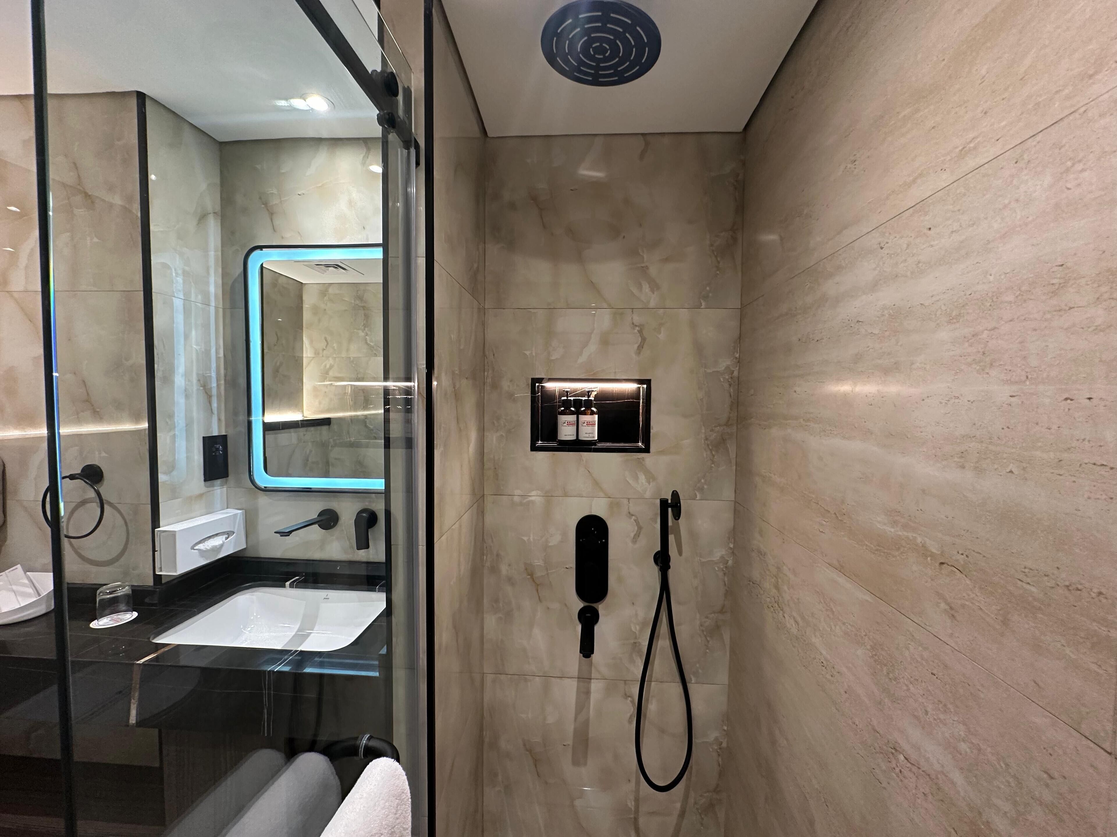 A modern bathroom with a glass shower enclosure, a built-in sink, and a mirror.
