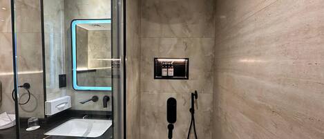 A modern bathroom with a glass shower enclosure, a built-in sink, and a mirror.