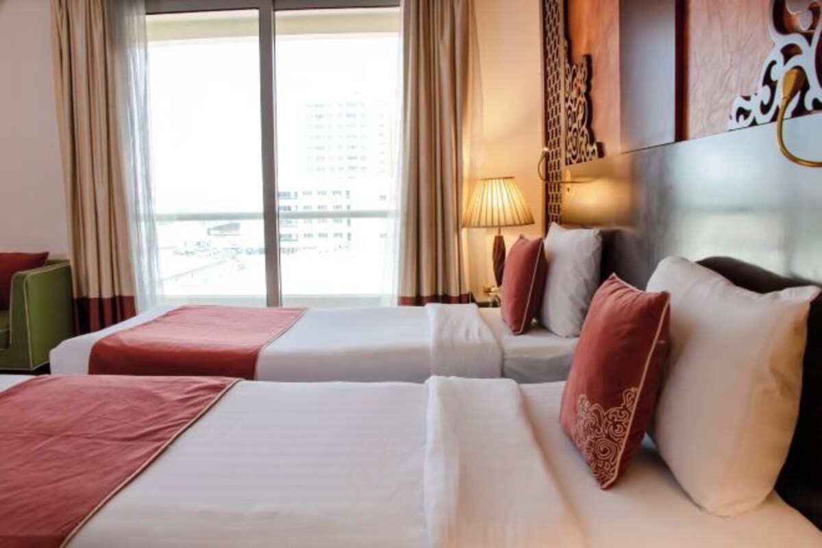 Een hotelkamer met twee bedden, uitzicht op de stad en een decoratieve wand.