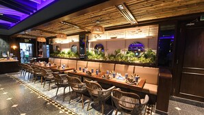 A restaurant with a long counter, wicker chairs, and a tiled floor. - Dubai Grand Hotel by Fortune (Dubai)