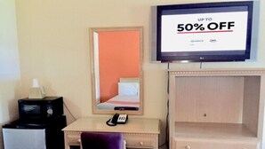 A hotel room with a bed, a desk with a chair, a television displaying a discount offer, a microwave, and a minibar. - Red Carpet Inn Great Lakes (North Chicago)