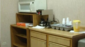 A kitchenette with a microwave, a coffee maker, and various kitchen items on the counter. - Red Carpet Inn Great Lakes (North Chicago)