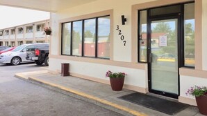 A building with a beige facade, a black door, and the number 3207 on the wall. There are two potted plants in front of the door. - Red Carpet Inn Great Lakes (North Chicago)