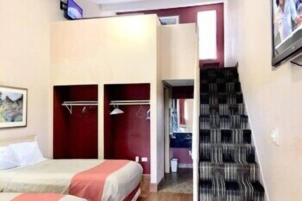 A bedroom with a bed, a wardrobe, and a staircase.