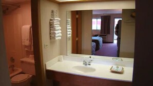 A bathroom with a sink, mirror, and towels. - Red Carpet Inn Great Lakes (North Chicago)