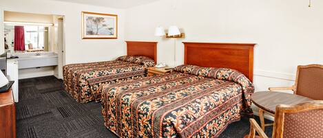 Une chambre d’hôtel avec deux lits, un bureau, une chaise et une lampe.
