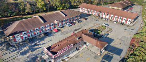 Un motel con varias unidades, un estacionamiento y un pequeño edificio que dice 'Red Carpet Inn'.