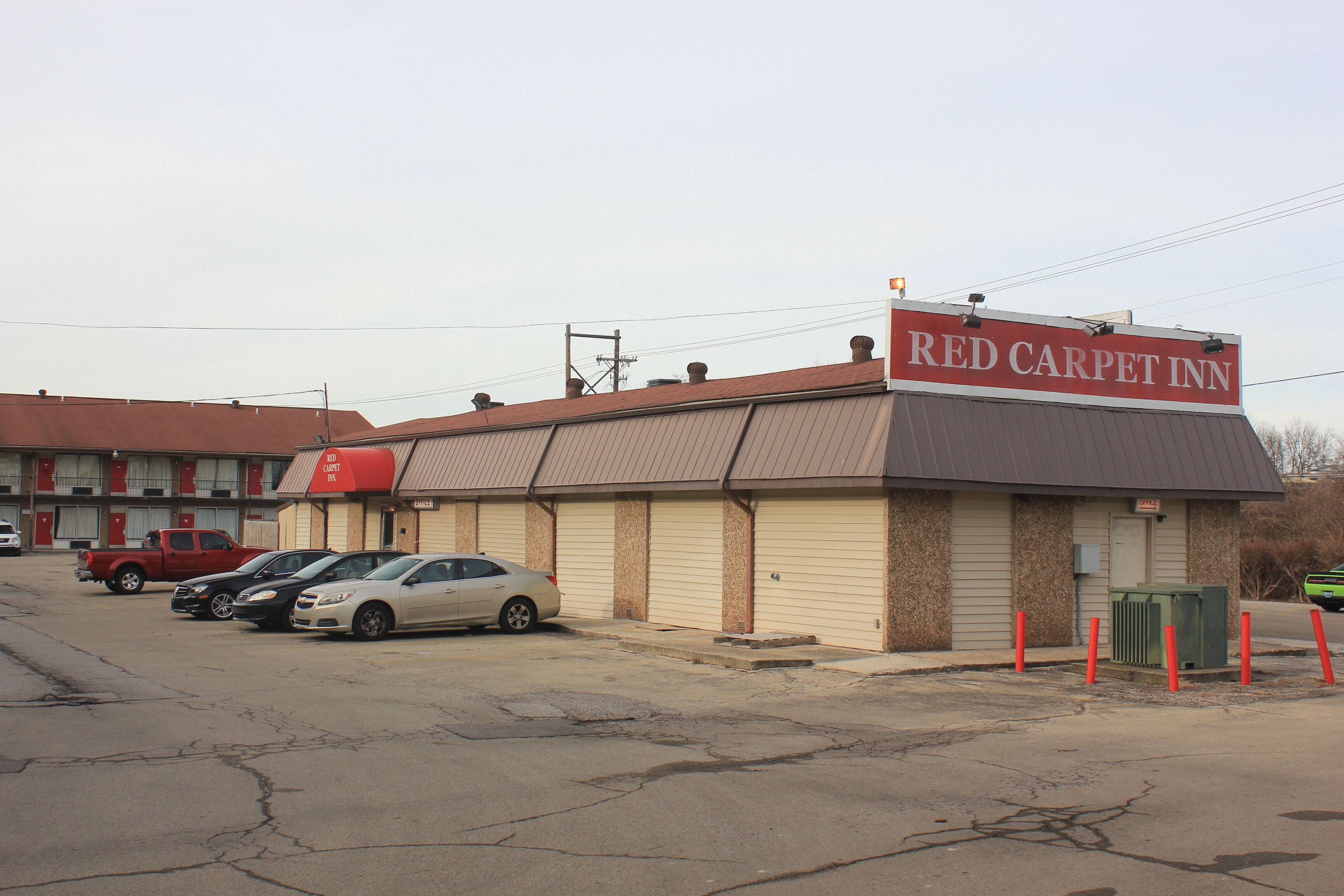 A Red Carpet Inn with a parking lot containing several cars.