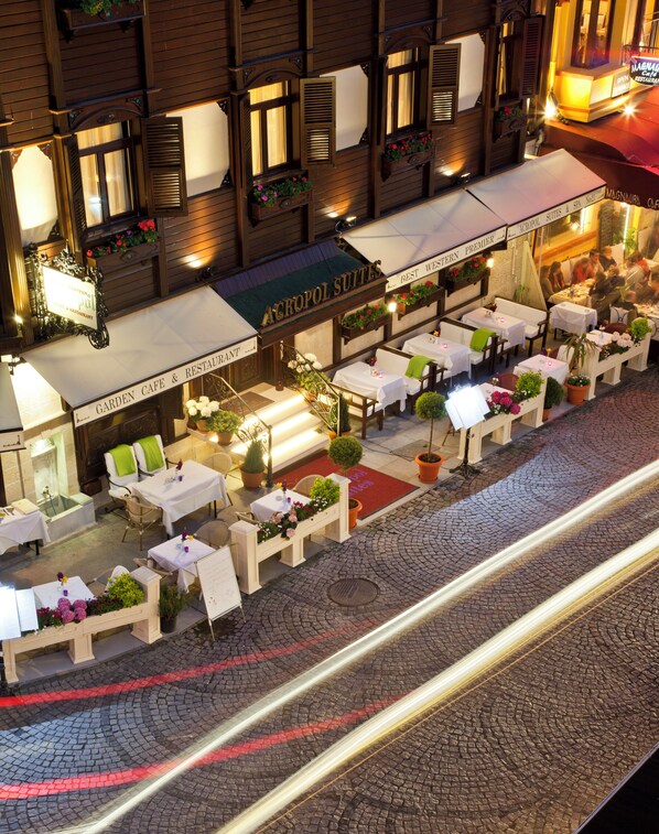 An outdoor café with tables and chairs, a sign for 'Acropolis Suites', and a cobblestone street. - GLK PREMIER Acropol Suites & Spa - Special Class  (Istanbul)
