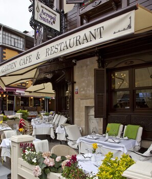 An outdoor seating area of a Garden Cafe & Restaurant with tables set for dining, surrounded by chairs and floral arrangements. - GLK PREMIER Acropol Suites & Spa - Special Class  (Istanbul)