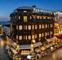 A multi-story building with a cafe and restaurant on the ground floor, featuring outdoor seating and a view of the water.