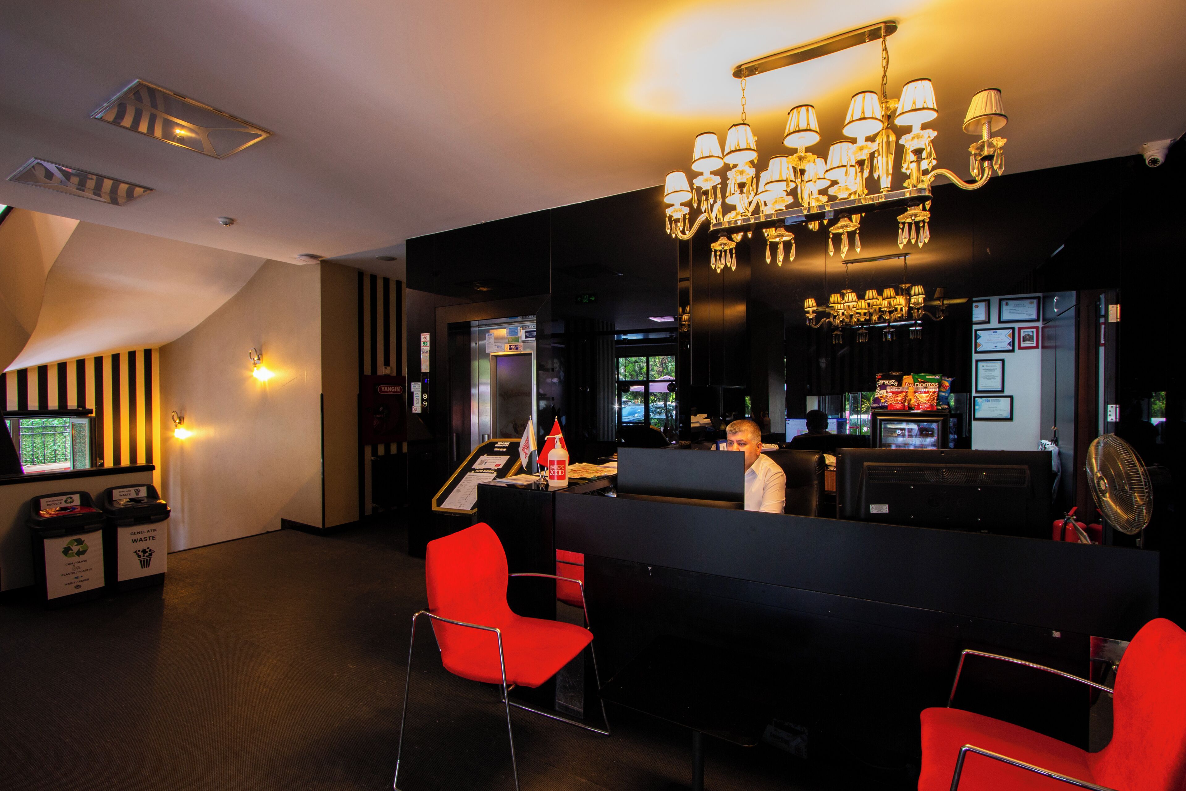 A bar area with a modern design, including a black counter, red chairs, and a chandelier.