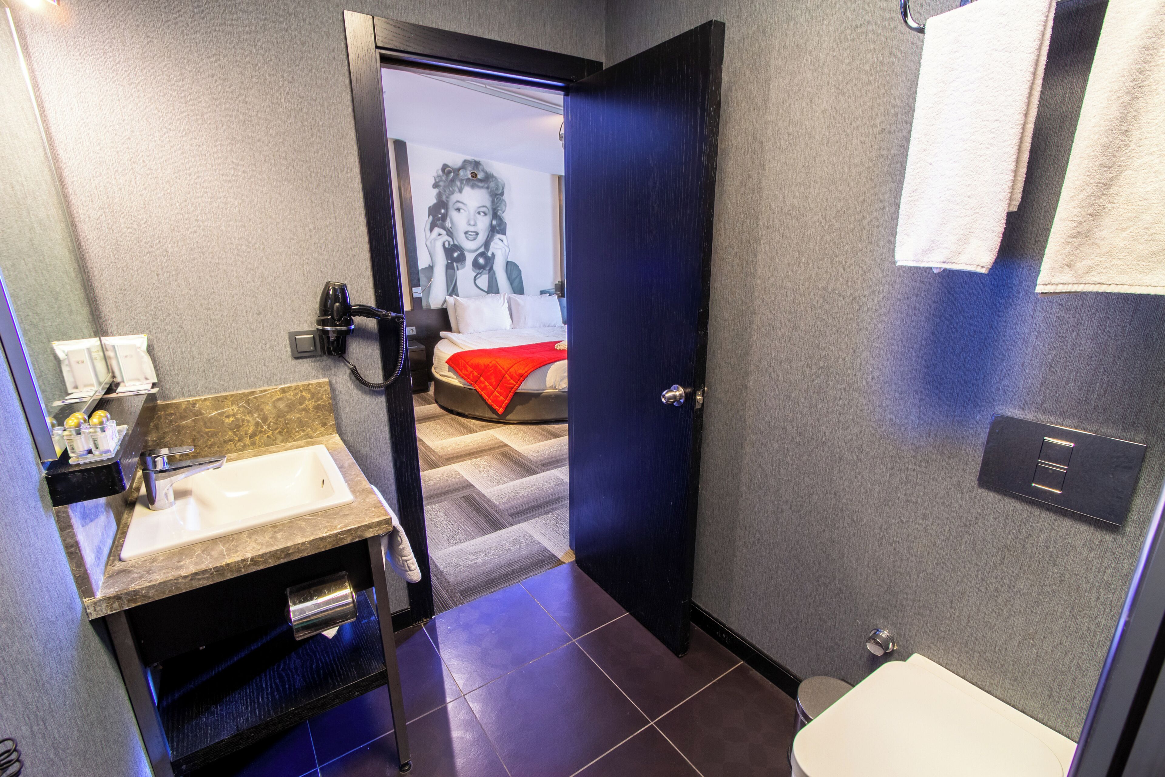Een badkamer met een wastafel, toilet en een deur naar een slaapkamer.
