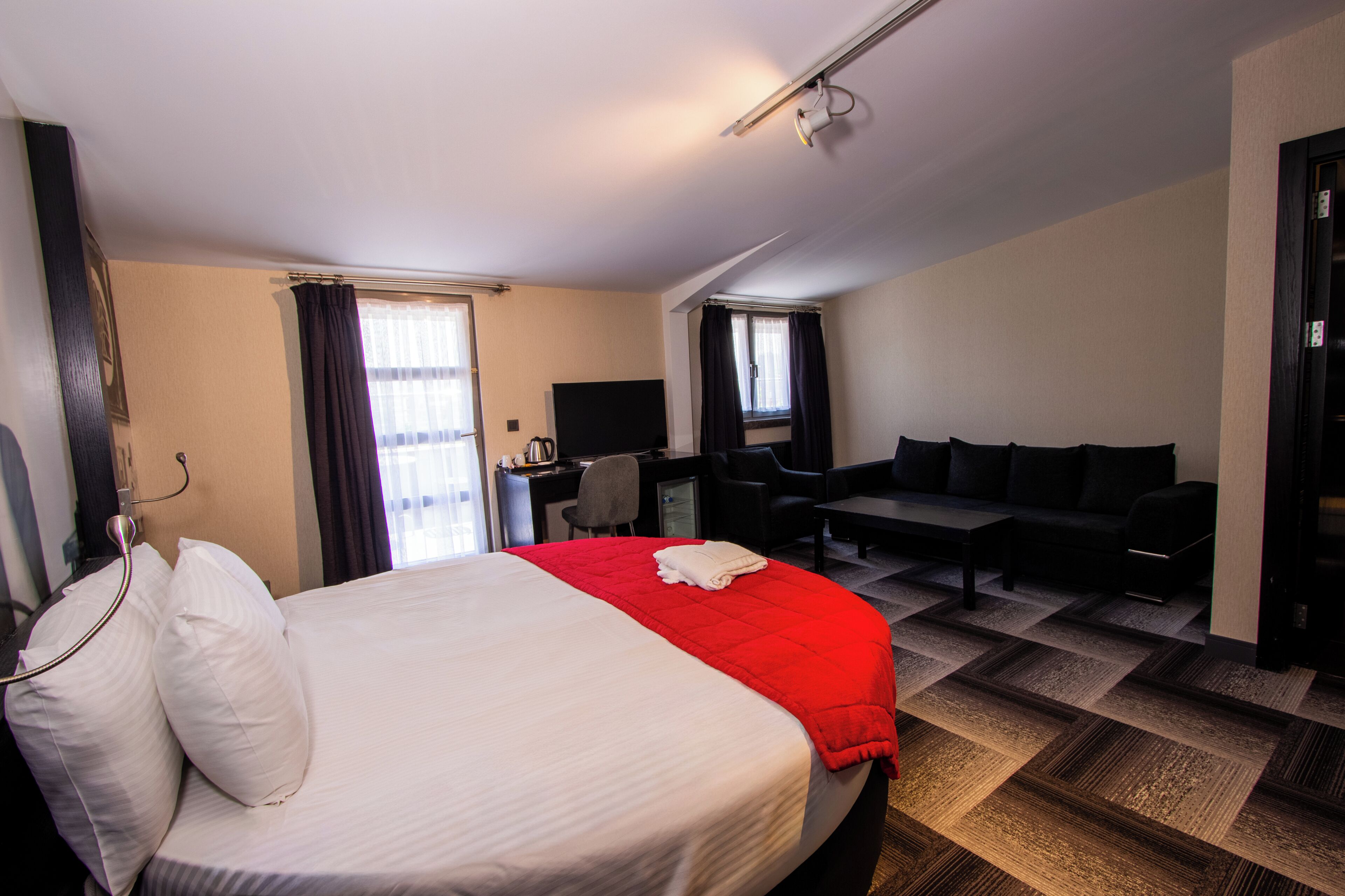 Una habitación de hotel con cama, escritorio, sillón, sofá y televisión.