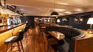 A bar area with stools, a bar counter, and a seating area with a booth and chairs.
