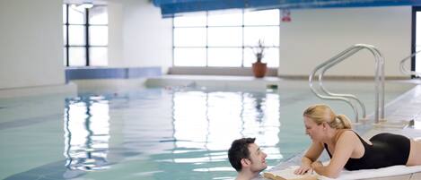 Una piscina con vista despejada al agua, suelo de azulejos y techo azul.