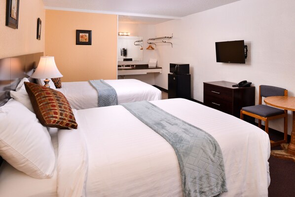 Habitación de hotel con dos camas, un escritorio, una silla, un televisor y un minibar.