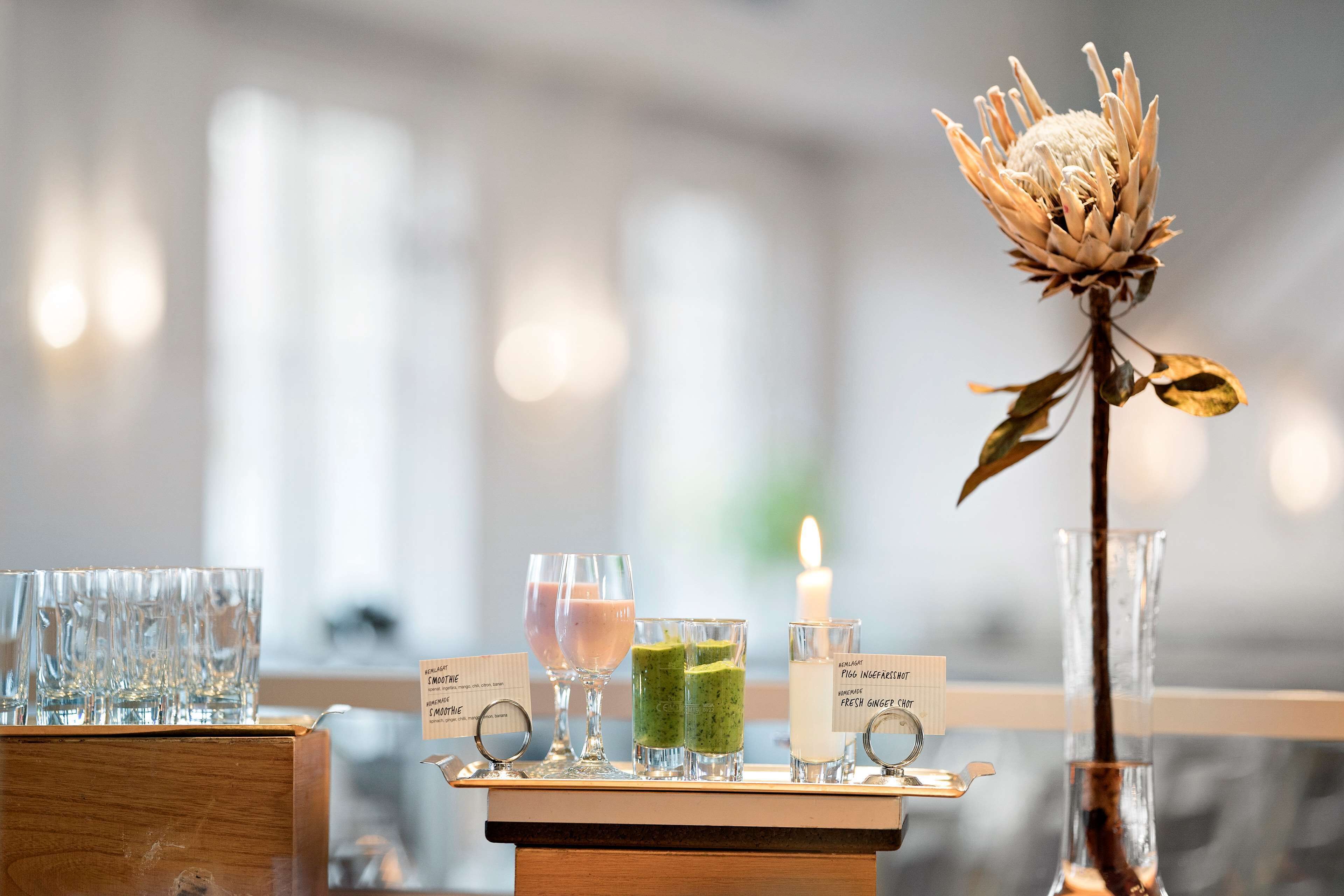 A bar area with glasses of drinks, a candle, and a flower centerpiece.