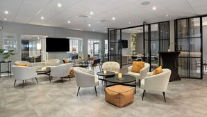 A modern lounge area with white armchairs, a coffee table, and a glass partition. - Best Western Vrigstad Vardshus (Vrigstad)