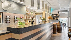 A bar area with a speckled countertop, wooden steps, and a variety of bottles and glasses. - Best Western Vrigstad Vardshus (Vrigstad)