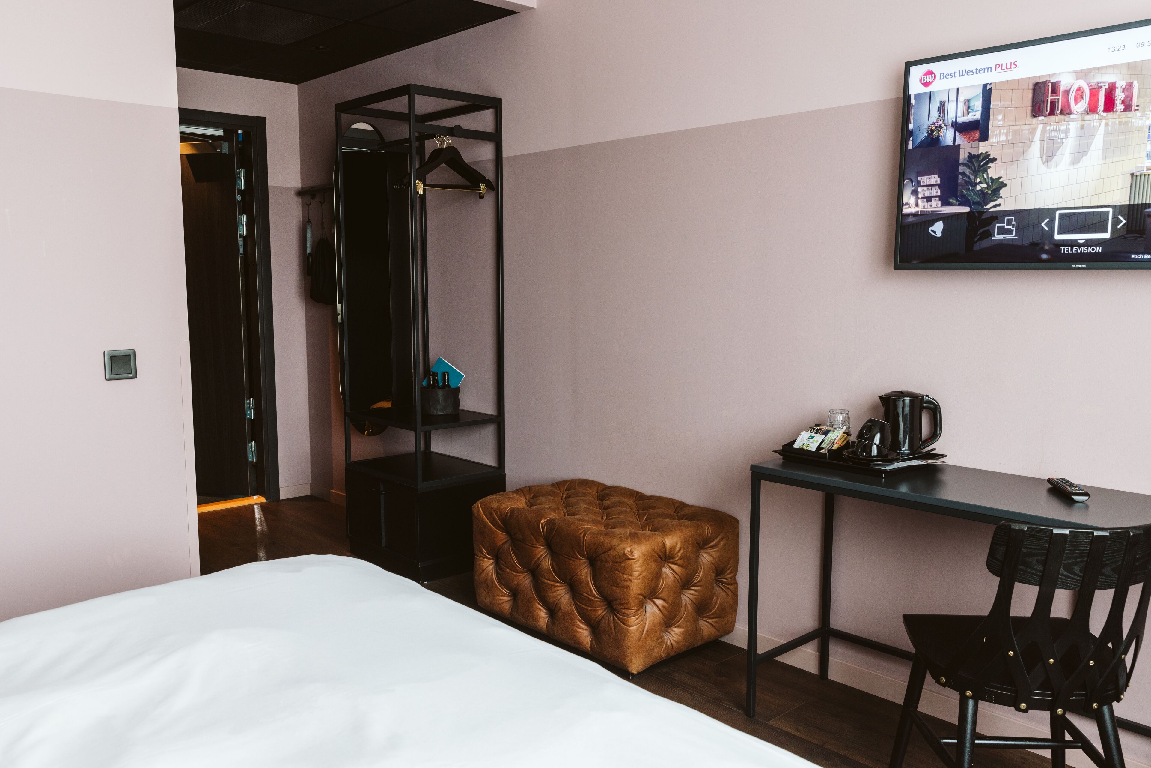 Una habitación de hotel con cama, escritorio, silla, televisor y armario.