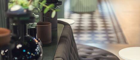 A modern bar area with a black cushioned bench, a green bar counter, and a white round table.