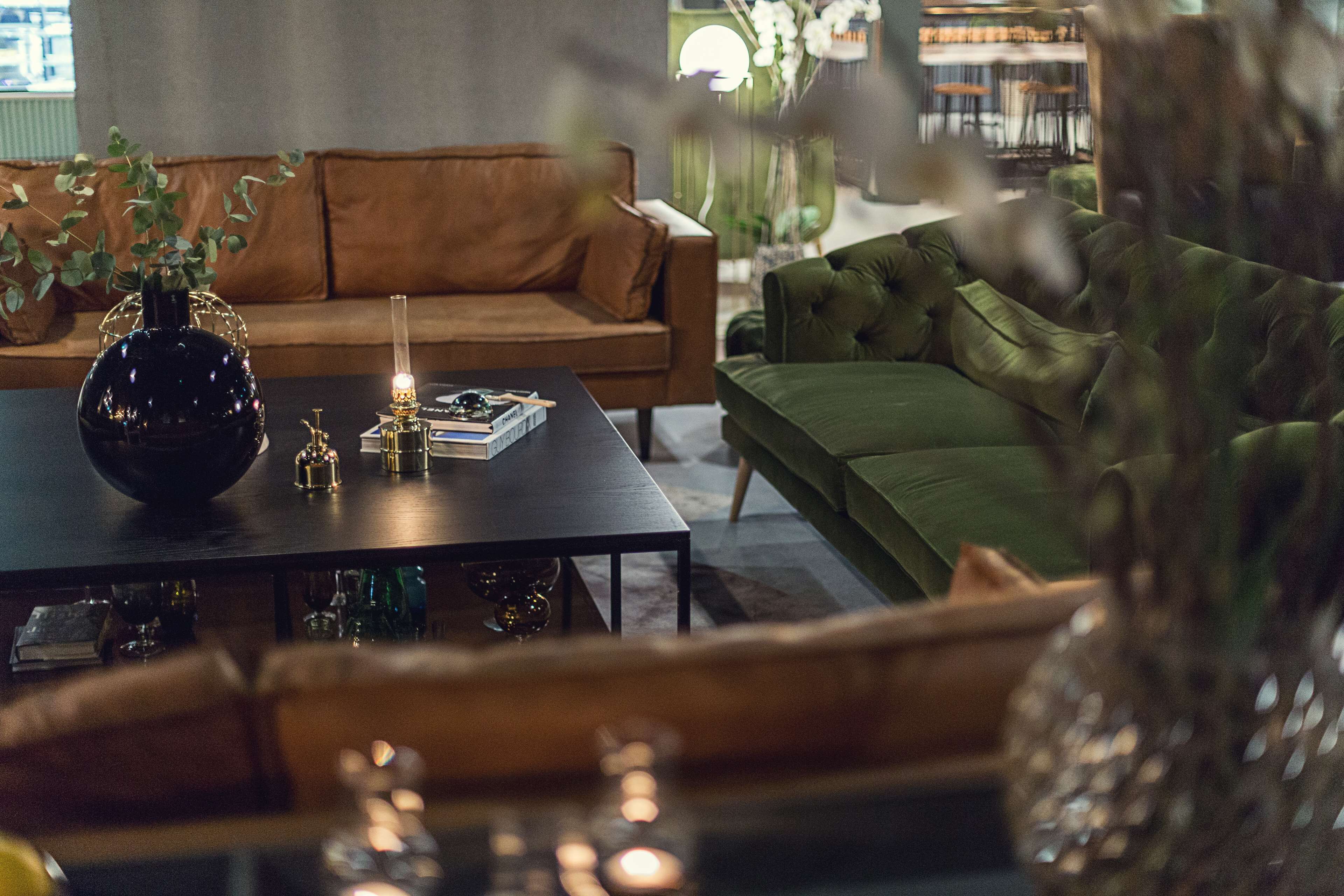 Un salon moderne avec une table basse de couleur sombre, un canapé vert et un canapé marron.