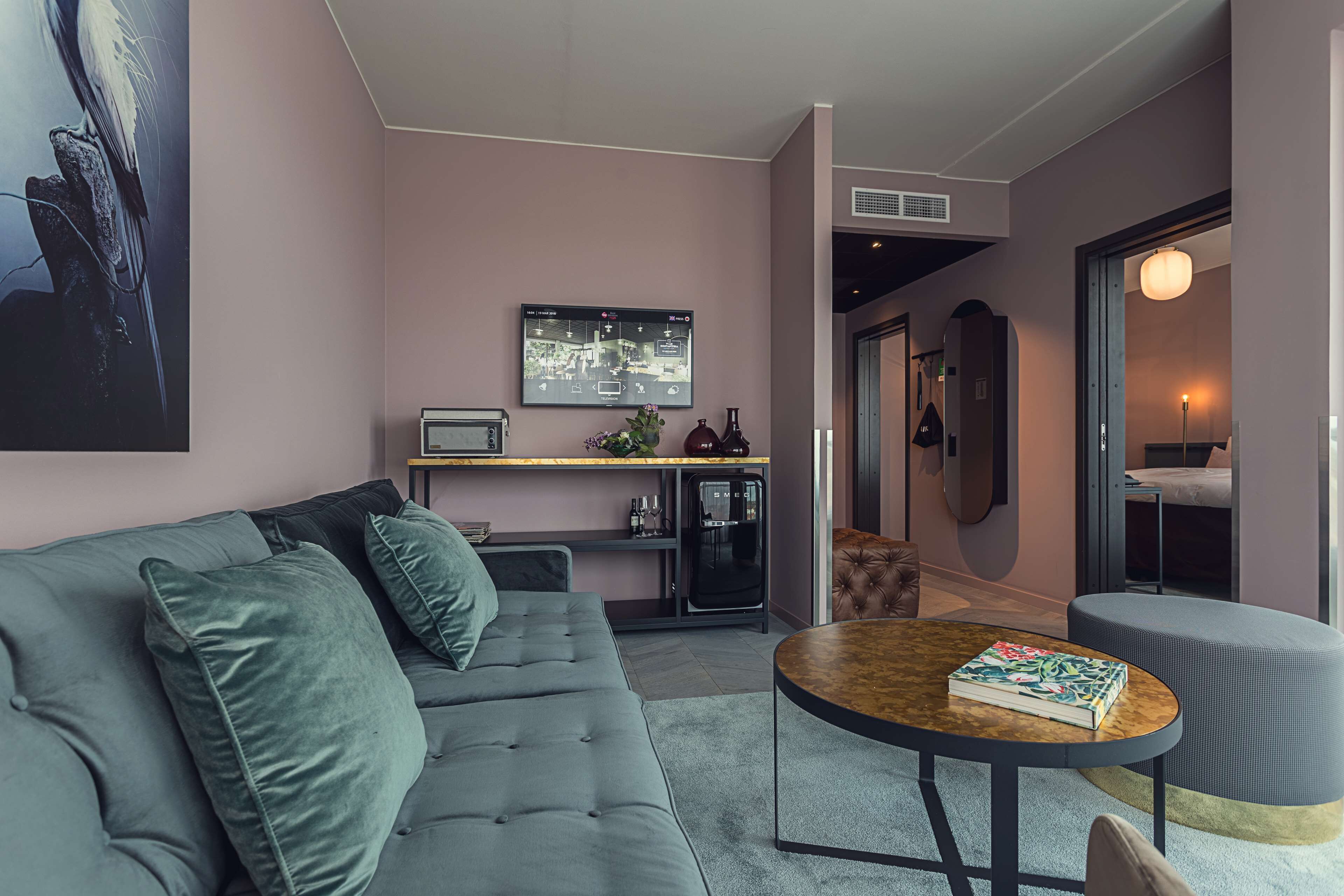 A modern living room with a grey sofa, a round coffee table, and a television mounted on the wall.