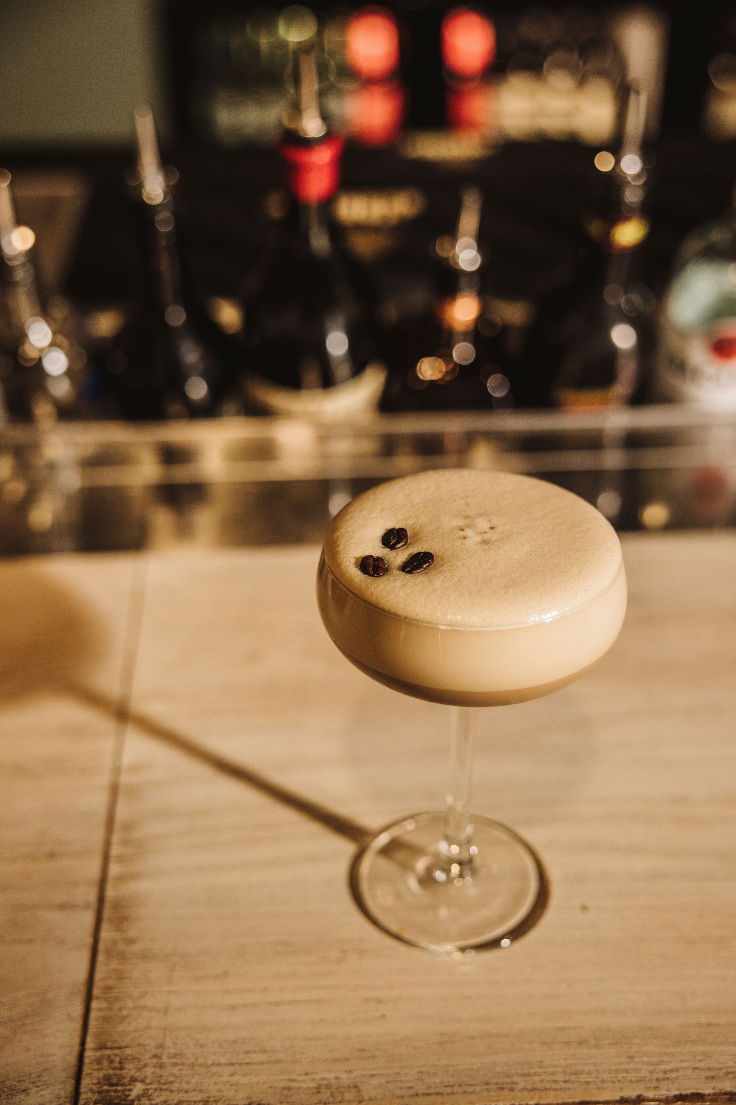 A cocktail in a stemmed glass on a wooden surface.