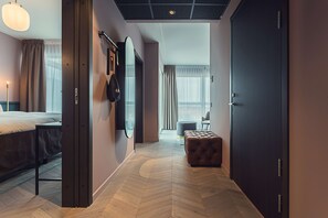 A modern hotel room with a bed, a seating area, and a large mirror.
