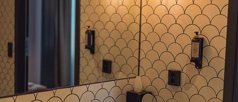A bathroom with a tiled wall, a sink, and two wall-mounted lights.