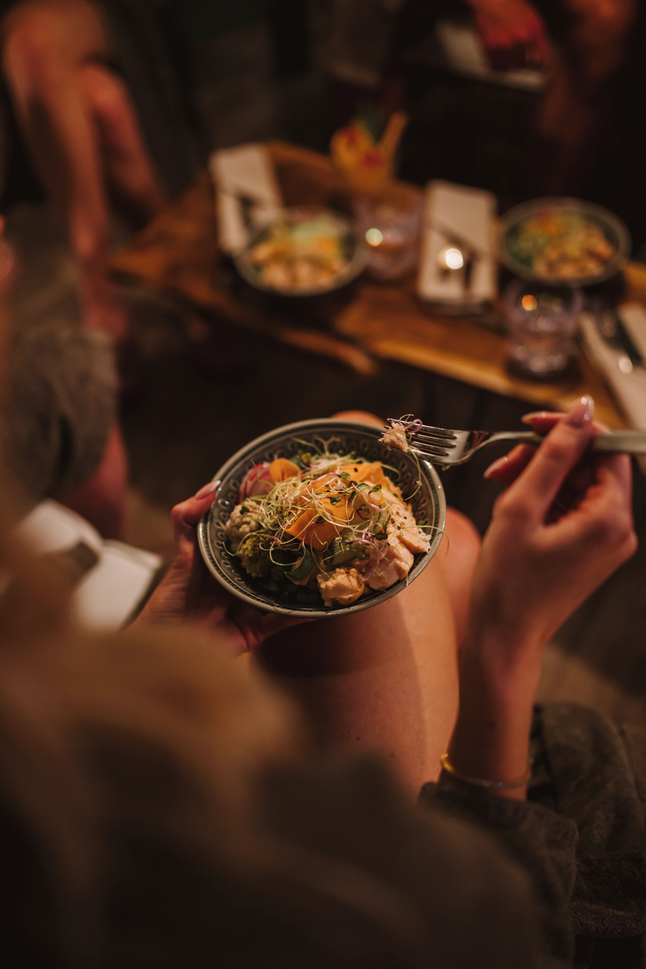 A person holding a bowl of food with a fork.
