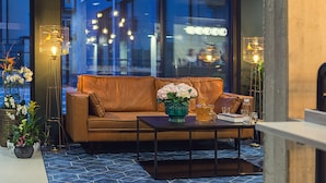 A modern interior with a leather sofa, a coffee table with a vase of flowers, and two floor lamps. - Best Western Plus Hus 57 (Angelholm)