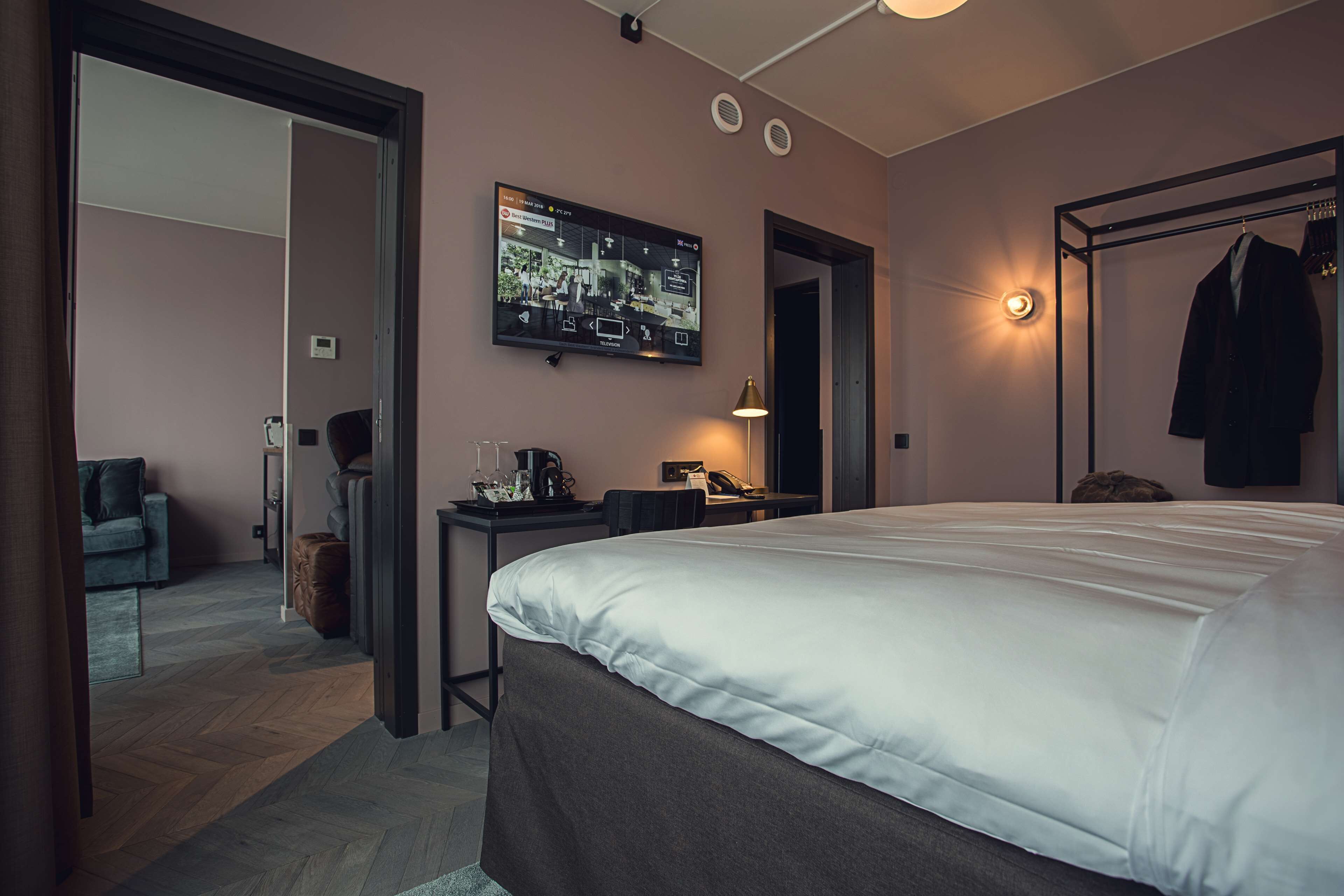 Ett modernt hotellrum med en stor säng, ett skrivbord, en tv och en garderob.