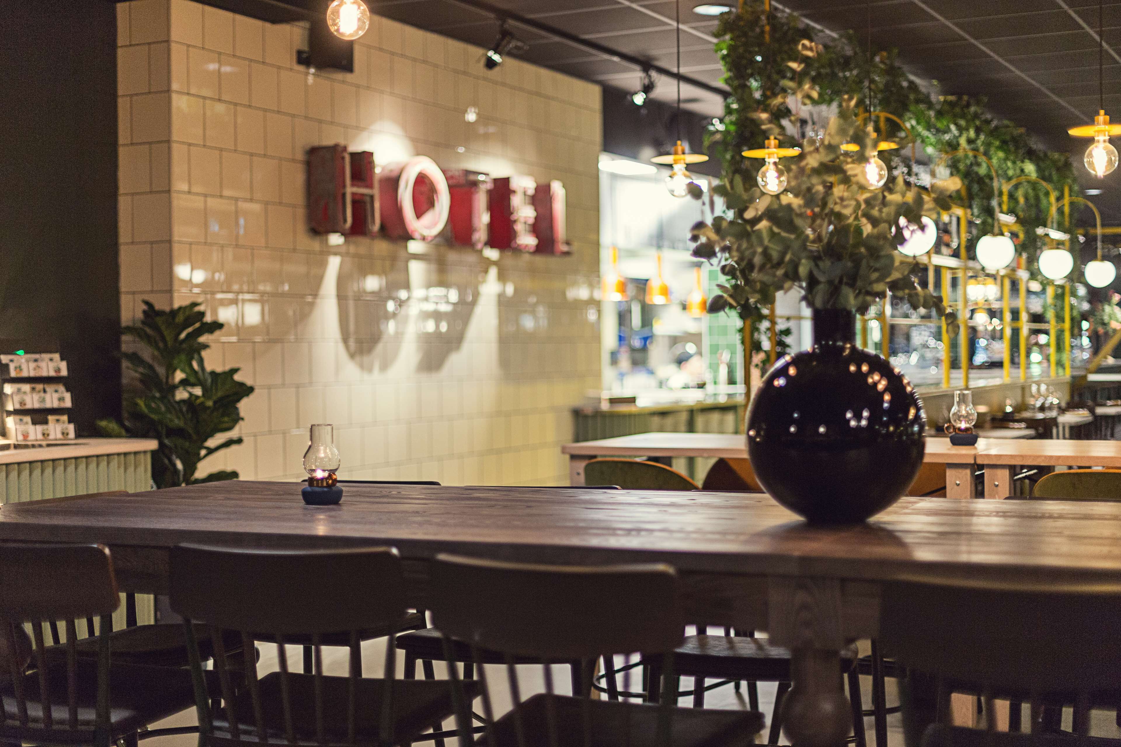 Interior de restaurante con una mesa redonda, sillas, luces colgantes y un letrero que dice 