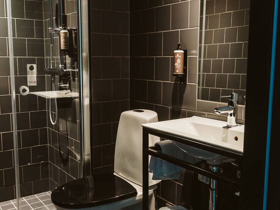 A modern bathroom with a glass-enclosed shower, a white sink, and a toilet.