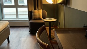 Una habitación de hotel con cama, una silla, una mesa, una lámpara y televisor.