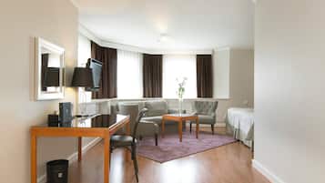 A hotel room with a sofa, a dining table, a TV, and a bed.