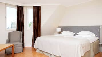 Habitación de hotel con cama, una silla, una mesa y ventana con cortinas.