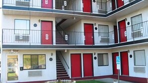 Un motel à plusieurs étages avec des portes rouges et des balcons.