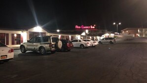 Red Carpet Inn -niminen hotelli, jonka parkkipaikka on täynnä autoja.