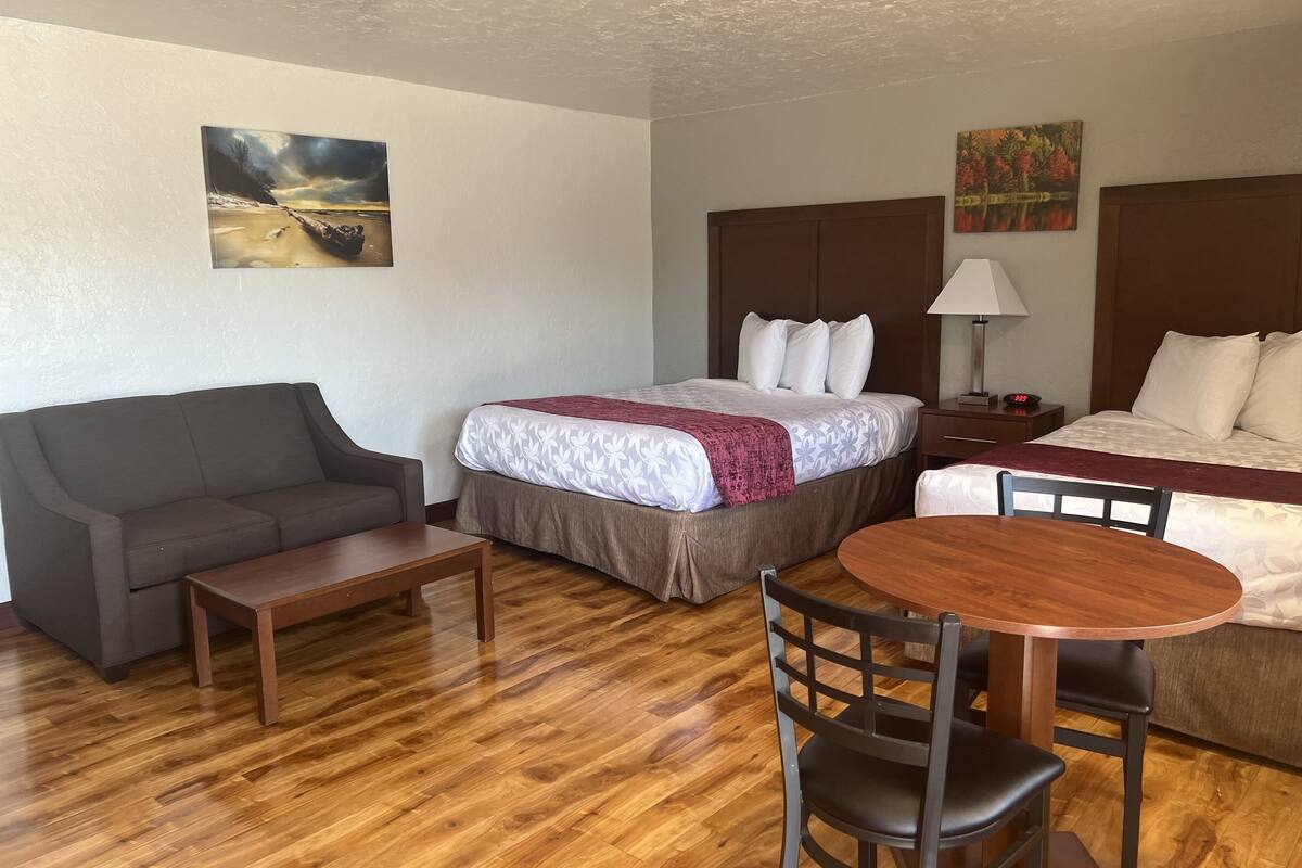 Une chambre d’hôtel avec un lit, un canapé, une petite table, une chaise et une table ronde.