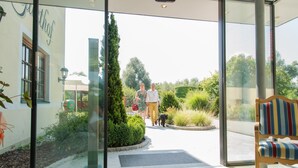 A hotel entrance with a glass door, a green mat, and a bench with striped cushions.