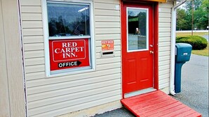 A small building with a red door and a window with a sign that reads "Red Carpet Inn Office." - Red Carpet Inn Duncannon (Duncannon)