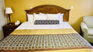 A hotel room with a bed, a nightstand with a lamp, and a chair. - Red Carpet Inn Duncannon (Duncannon)