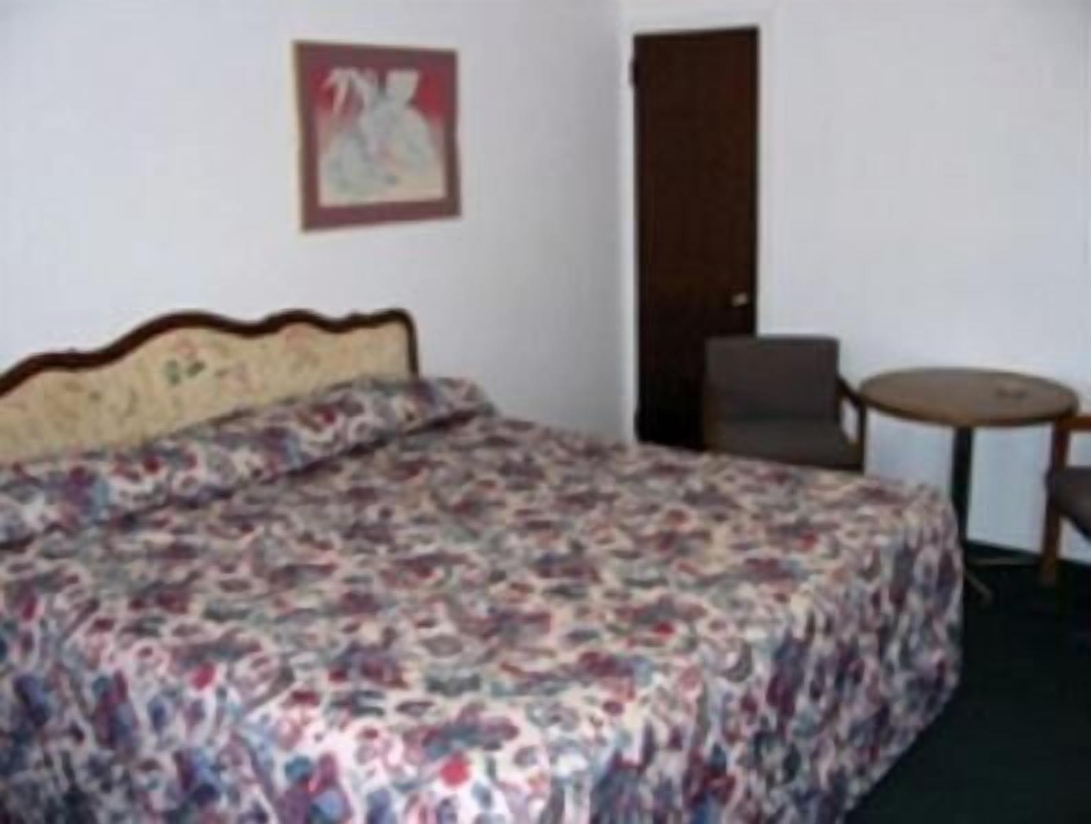 A room with a bed, a chair, a small table, and a door.