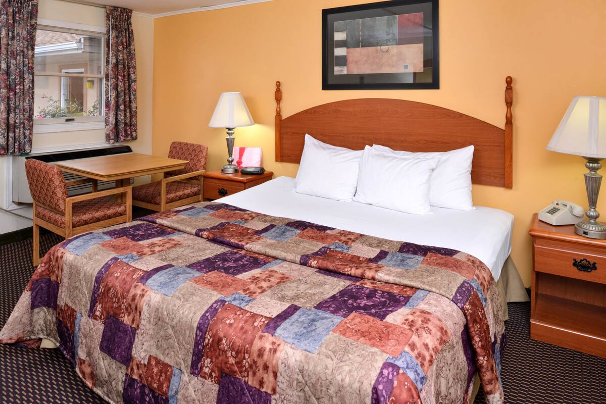 Una habitación de hotel con cama, escritorio, silla y mesita de noche.