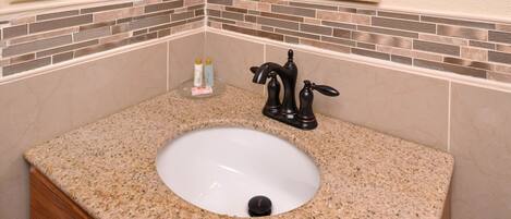 A bathroom with a granite countertop, a white sink, a black faucet, and a mirror above the sink.