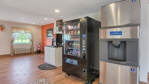 Ein Hotelzimmer mit Minibar, einem Kühlschrank mit Wasserspender, einer Kaffeemaschine und einem Vorhangfenster.